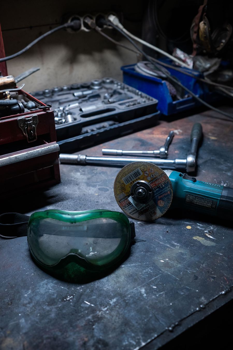 A workbench with an open toolbox, a socket set and safety goggles.